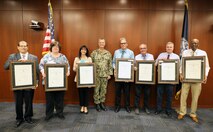 Naval Surface Warfare Center, Philadelphia Division (NSWCPD) Commanding Officer Capt. Joseph Darcy (center) presents NSWPCD personnel (pictured left to right holding awards) John Imbesi, Marie Nichols, Theresa Steck, James Brigham, Shawn Egnak, Douglas McDonnell, and Frederick Good with Career Service Awards for 40 years of service to the U.S. federal government during NSWCPD’s Fiscal Year (FY) 2023 Second Quarter Awards Ceremony on June 8, 2023. (U.S. Navy photo by Phillip Scaringi/Released)