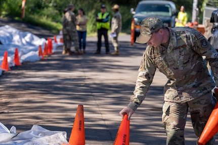 Senior Airman Maxim Murphy with the 647th Civil Engineering Squadron sets up safety cones as part of Naval Facilities Engineering Systems Command (NAVFAC) Public Works Department and Joint Task Force-Red Hill’s (JTF-RH) hazard material spill recovery operation at the Red Hill Bulk Fuel Storage Facility (RHBFSF) in Halawa, Hawaii, Dec. 2, 2022. Remediation of the spill site through excavation and removal of contaminated surfaces and material was immediately initiated after an estimated 1,100 gallons of aqueous film forming foam (AFFF) concentrate spilled from the fire suppression system at RHBFSF Adit 6 on Nov. 29, 2022. JTF-RH was established by the Department of Defense to ensure the safe and expeditious defueling of the RHBFSF. (DoD photo by Staff Sgt. Orlando Corpuz)