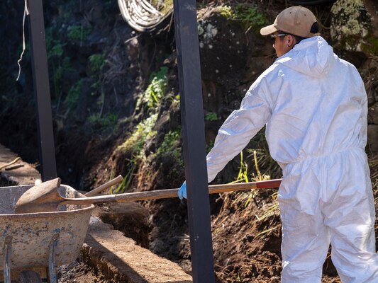 A Naval Facilities Engineering Systems Command (NAVFAC) Fleet Logistics Center (FLC) Pearl Harbor employee uses a shovel to relocate contaminated soil onto a wheelbarrow as part of NAVFAC Public Works Department and Joint Task Force-Red Hill’s (JTF-RH) hazard material spill recovery operation at the Red Hill Bulk Fuel Storage Facility (RHBFSF) in Halawa, Hawaii, Dec. 2, 2022. Remediation of the spill site through excavation and removal of contaminated surfaces and material was immediately initiated after an estimated 1,100 gallons of aqueous film forming foam (AFFF) concentrate spilled from the fire suppression system at RHBFSF Adit 6 on Nov. 29, 2022. JTF-RH was established by the Department of Defense to ensure the safe and expeditious defueling of the RHBFSF. (U.S. Air National Guard photo by Staff Sgt. Orlando Corpuz)