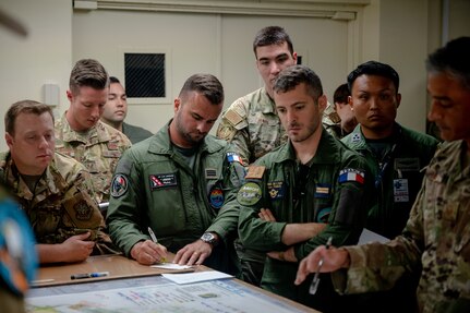 Members from multiple nations air forces gather together to plan an elephant walk during Mobility Guardian 23 in Andersen Air Force Base, Guam, July 18, 2023. MG23 is a multilateral exercise involving joint foreign partners to showcase coalition ability in the INDOPACOM area of responsibility.  (U.S. Air Force photo by Tech. Sgt. Sean Carnes)