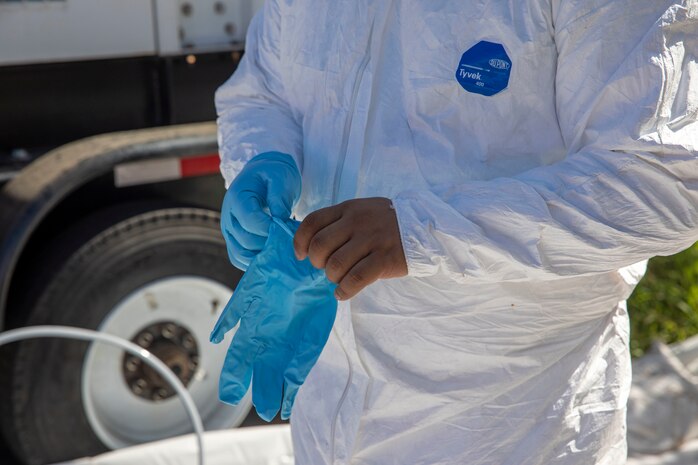 A Naval Facilities Engineering Systems Command (NAVFAC) Fleet Logistics Center (FLC) Pearl Harbor employee puts on gloves before entering the spill site as part of NAVFAC Public Works Department and Joint Task Force-Red Hill’s (JTF-RH) hazard material spill recovery operation at the Red Hill Bulk Fuel Storage Facility (RHBFSF) in Halawa, Hawaii, Dec. 1, 2022. Remediation of the spill site through excavation and removal of contaminated surfaces and material was immediately initiated after an estimated 1,100 gallons of aqueous film forming foam (AFFF) concentrate spilled from the fire suppression system at RHBFSF Adit 6 on Nov. 29, 2022. JTF-RH was established by the Department of Defense to ensure the safe and expeditious defueling of the RHBFSF. (DoD photo by Spc. Matthew Mackintosh)