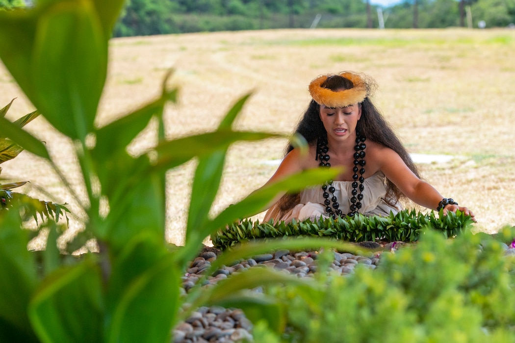 hula dancer places ti leaf lei at crypt