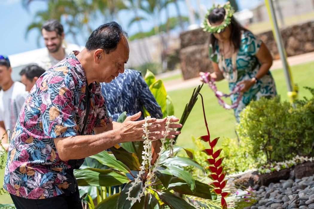 Man leans over to place lei at crypt
