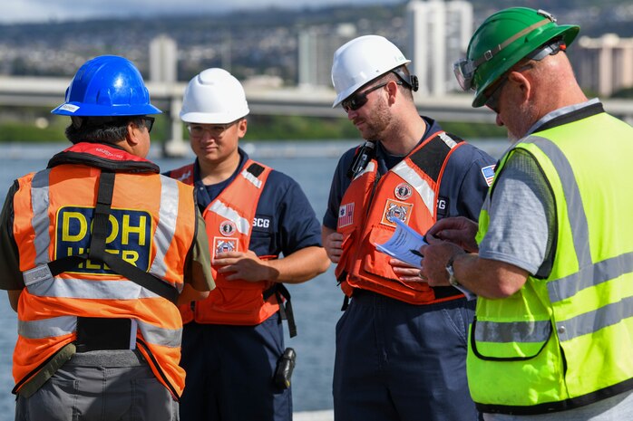 U.S. Coastguardsmen speak with a member of the Department of Health during an unpacking operation onboard Joint Base Pearl Harbor-Hickam (JBPHH), Hawaii, Oct. 27, 2022. The unpacking operation will remove approximately one million gallons of fuel from three primary fuel pipelines connecting the Red Hill Bulk Fuel Storage Facility (RHBFSF) to fuel points on JBPHH. JTF-RH was established by the Department of Defense to ensure the safe and expeditious defueling of the RHBFSF. (DoD photo by Cpl. Luke Cohen)