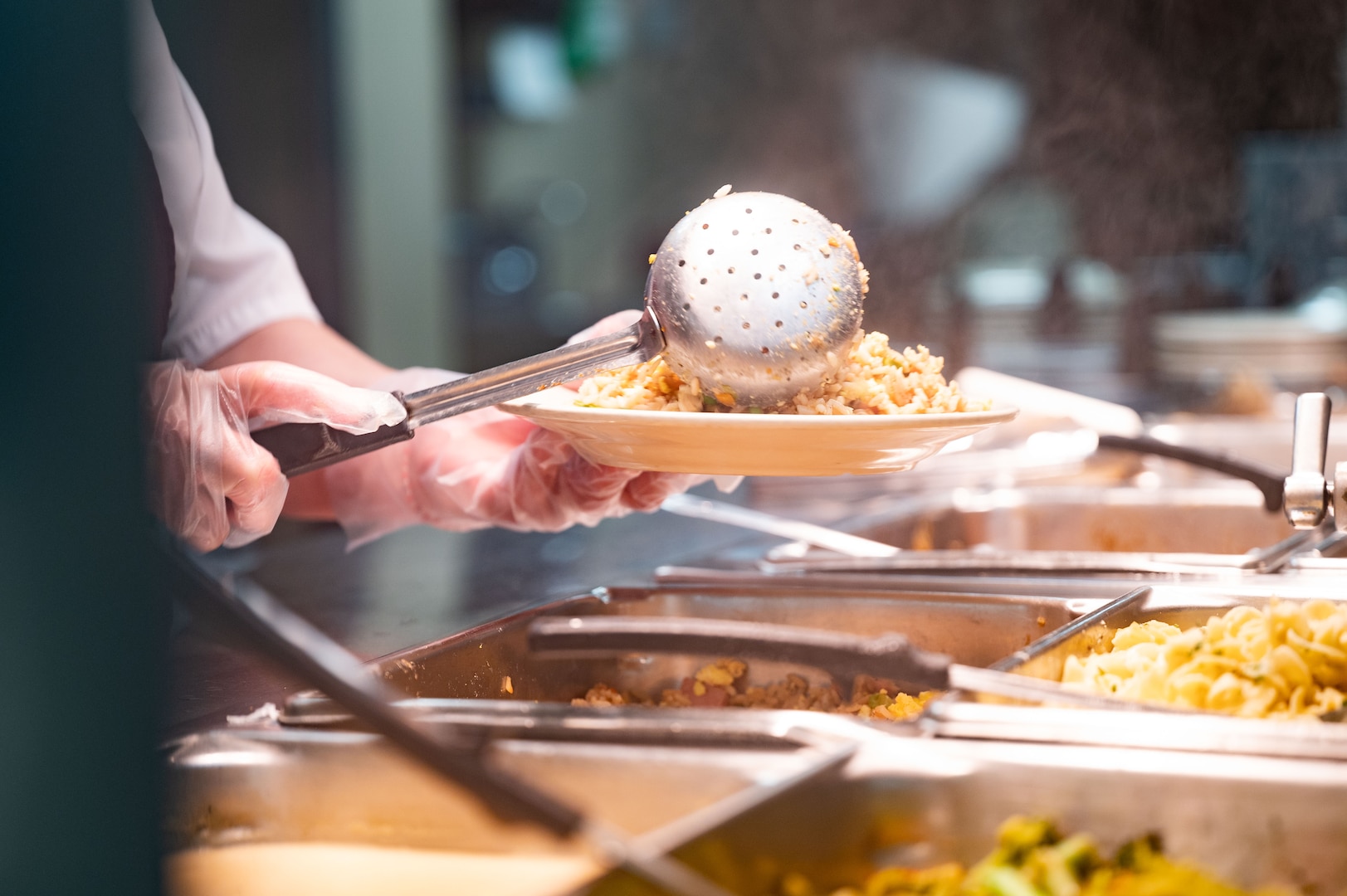 Server scoops food onto plate in the dining facility