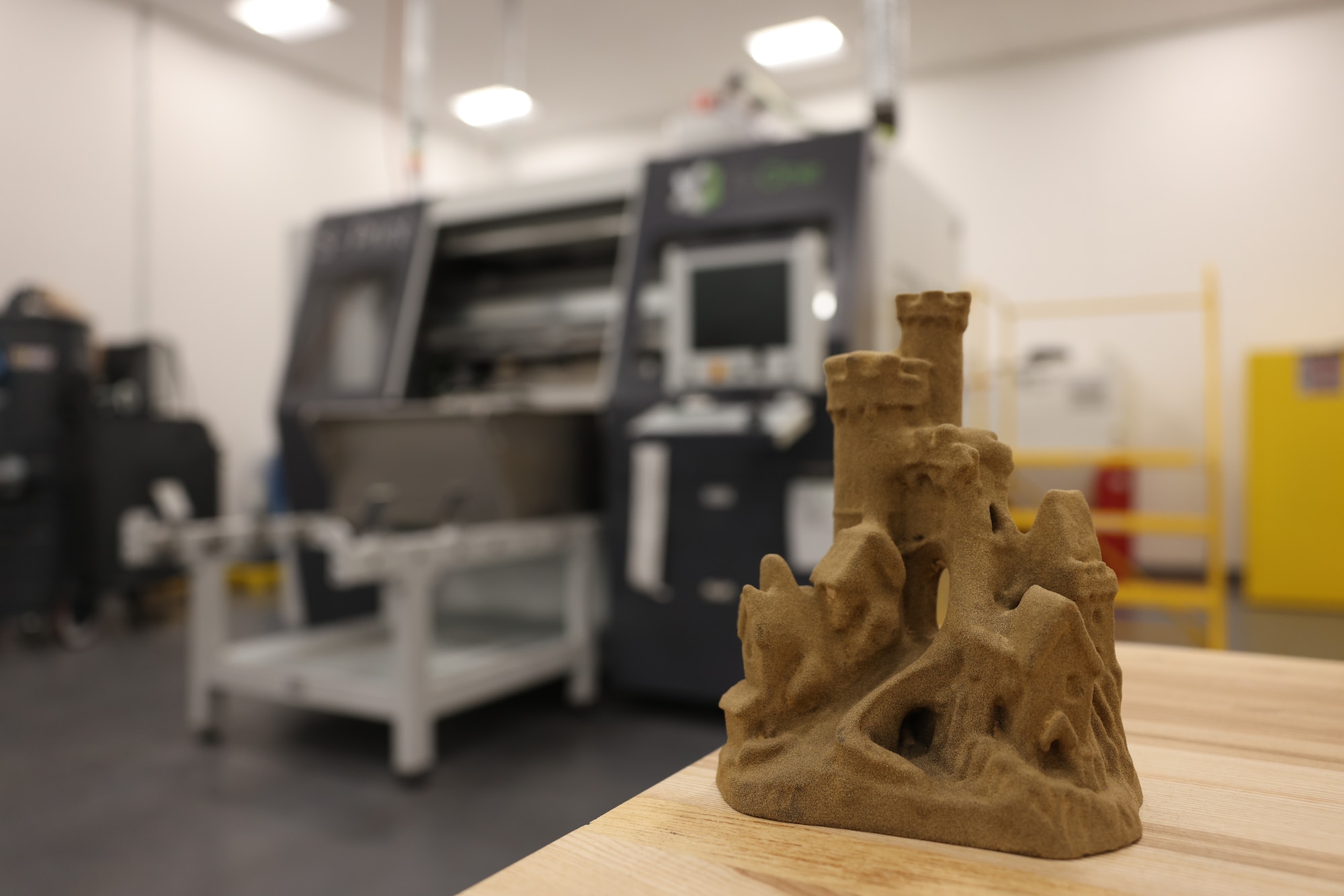 Sand castle sitting in foreground against industrial machine in background