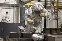 Man wearing fire suit pouring molten aluminum