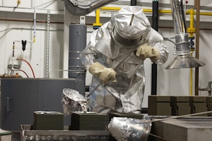 Man wearing fire suit pouring molten aluminum