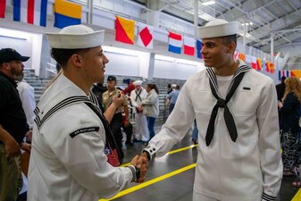 Aviation Boatswain's Mate (Fuel) 1st Class Dominique Williams, left, a recruit division commander at Recruit Training Command (RTC), congratulates his brother Seaman Recruit Tyriek Williams after graduating boot camp at RTC in Great Lakes, Illinois.