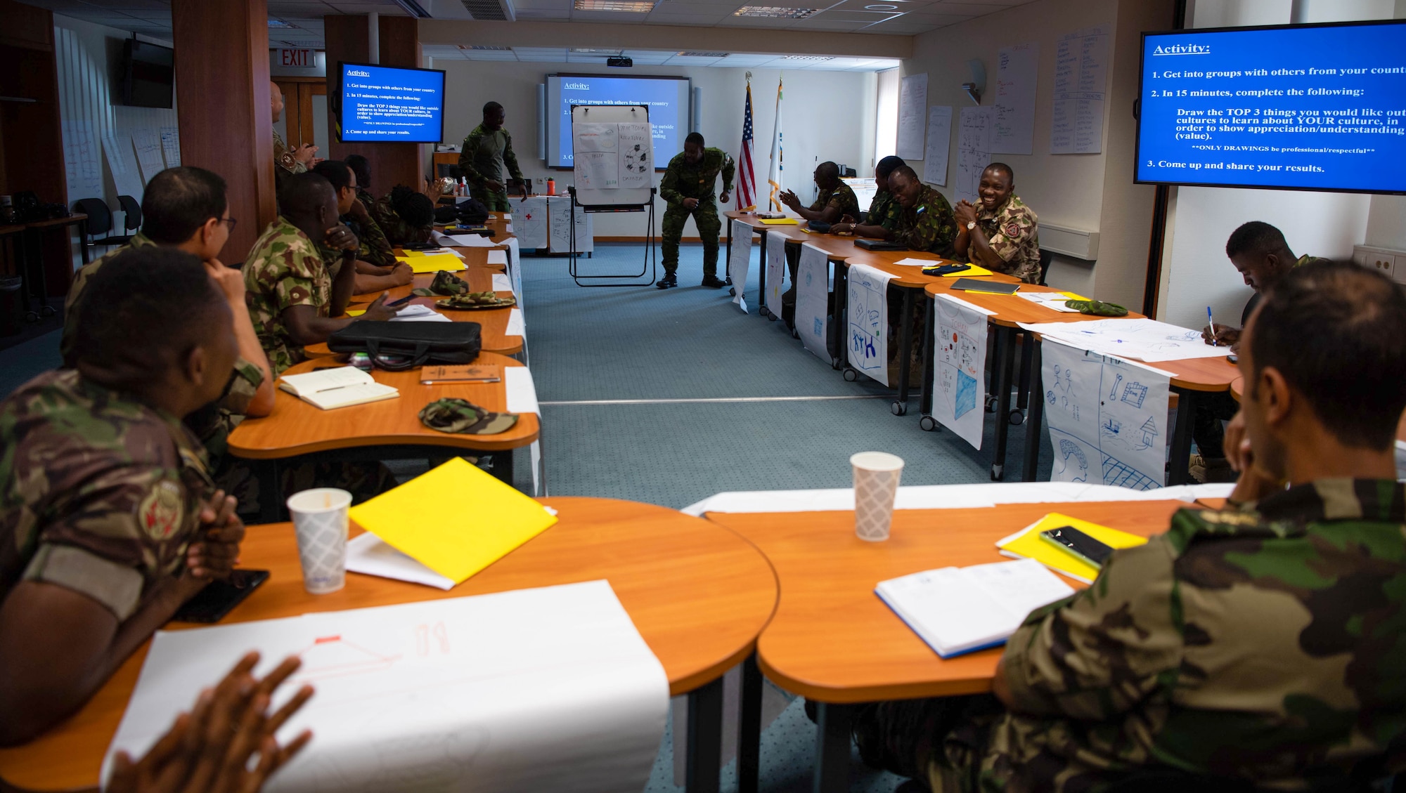 Côte d’Ivoire Air Force Capt. Comoe Essey, Inter-African Professional Development Seminar student, center left, and Lt. Johan Cedric Bombo IAPDS student, center right, present a Côte d'Ivoire cross-cultural competence brief to peers during the Inter-European Air Forces Academy at Kapaun Air Station, Germany, July 18, 2023.