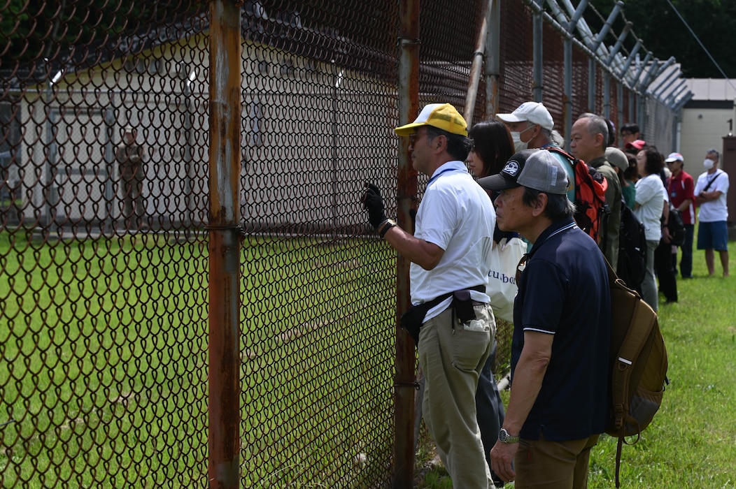 Participants of a Misawa Friendship Tour look on from the fence-line during a military working dog (MWD) demonstration at Misawa Air Base, Japan, July 14, 2023. MWDs are vital to many military operations and help with a variety of missions.