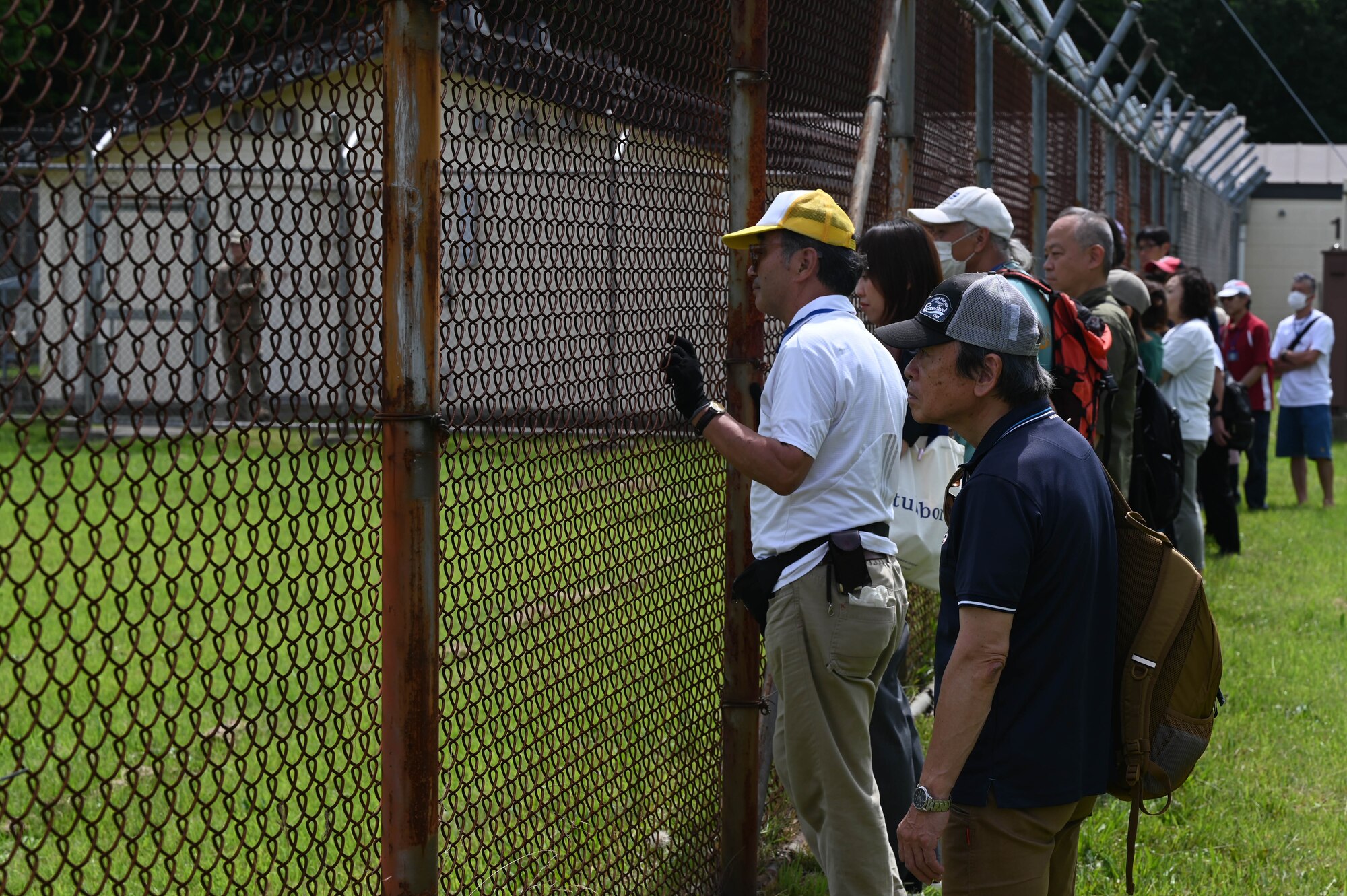 Participants of a Misawa Friendship Tour look on from the fence-line during a military working dog (MWD) demonstration at Misawa Air Base, Japan, July 14, 2023. MWDs are vital to many military operations and help with a variety of missions.