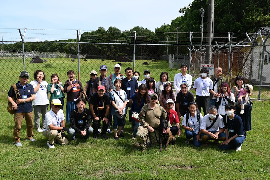 U.S. Air Force Staff Sgt Tyler Parker, 35th Security Forces military working dog handler, poses with participants of a Misawa Friendship Tour at Misawa Air Base, July 14, 2023.