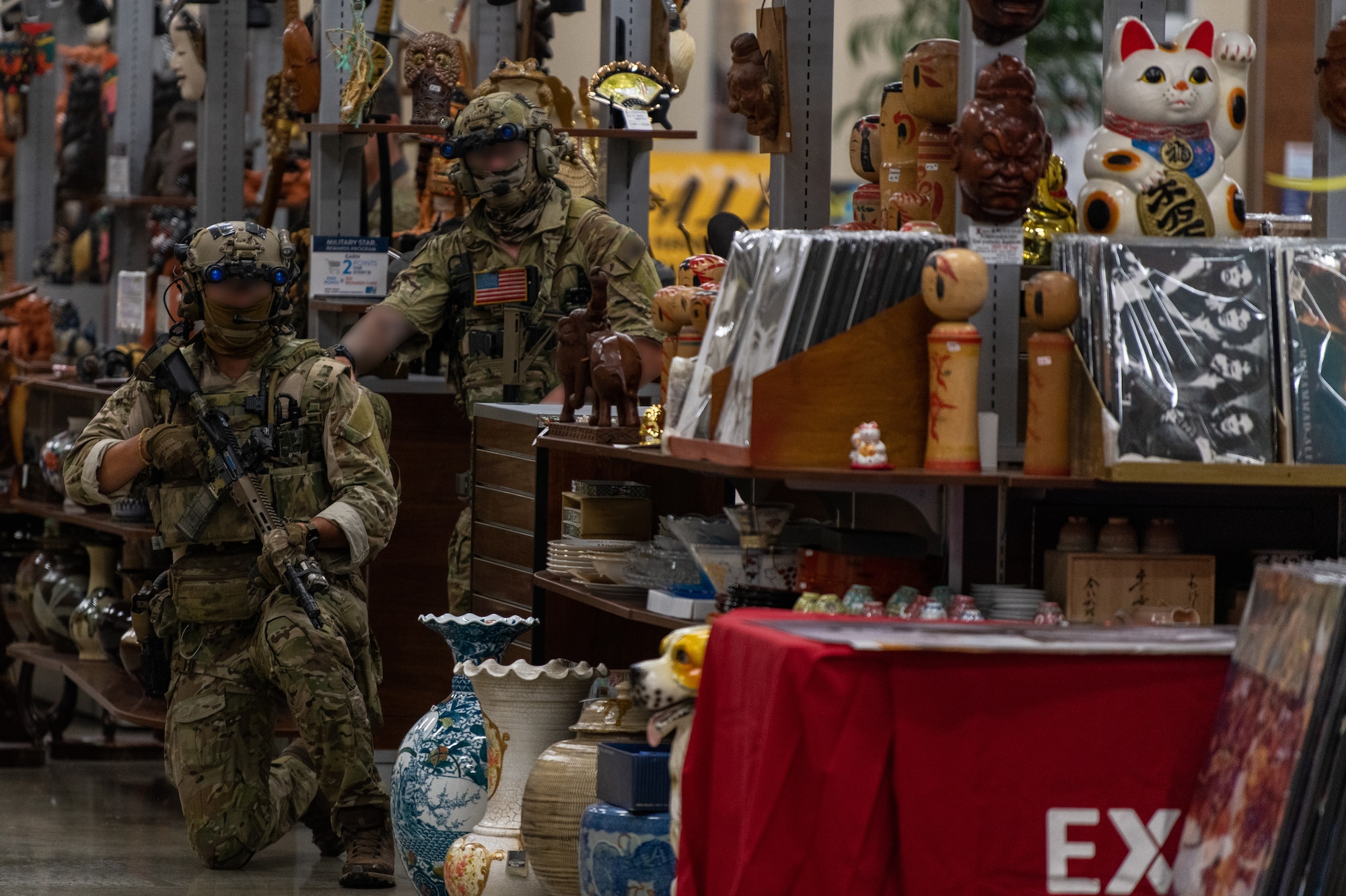 Two U.S. Army Green Berets take cover by a shop stand.