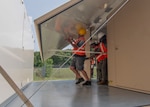 People erect the walls of a shipping container that turns into an office space.