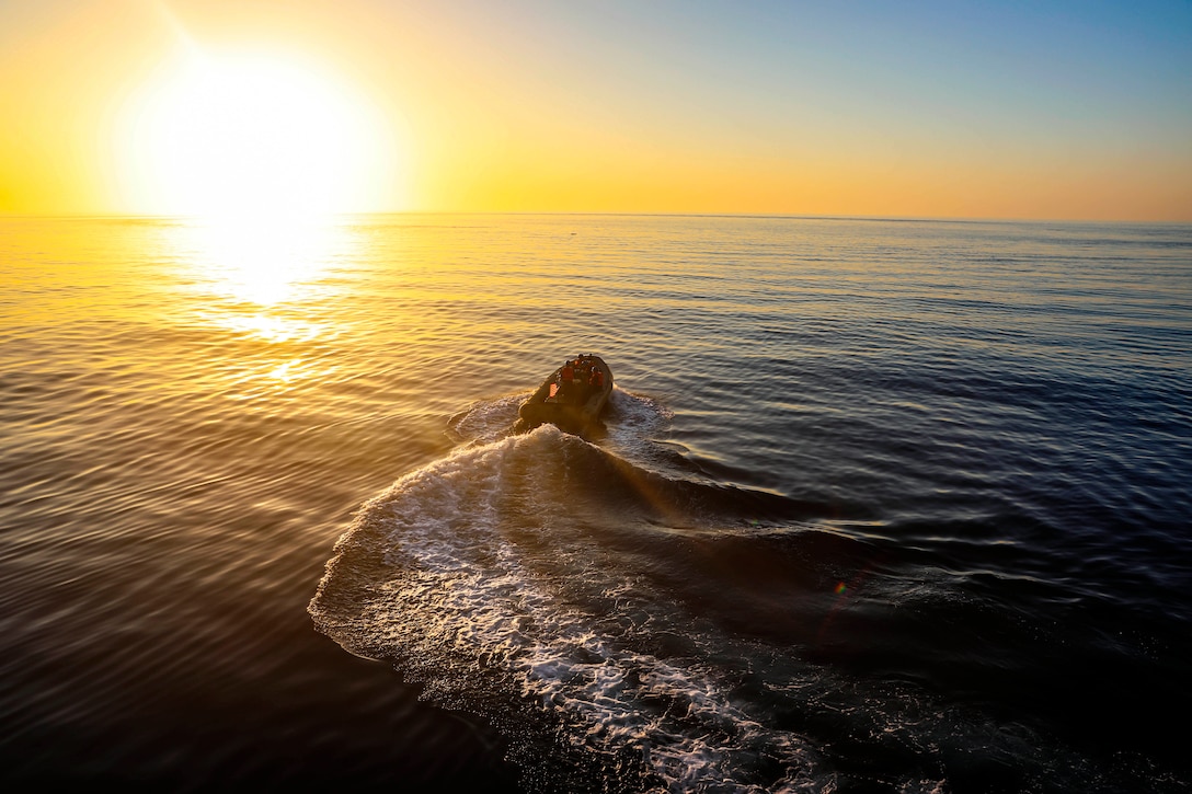 A small boat operates in the sea at twilight.