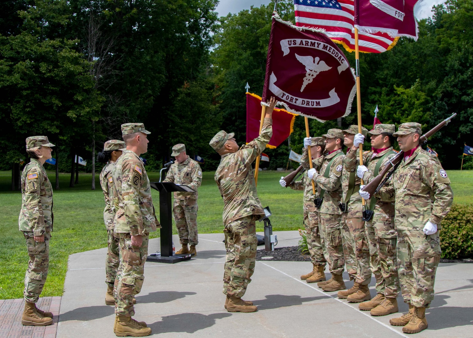 Command Sgt. Maj. Joey A. Mendez (center), the acting senior enlisted leader of the U.S. Army Medical Department Activity, Fort Drum, receives the unit’s flag, or colors, prior to handing it off to the outgoing commander during the MEDDAC’s change of command ceremony at Memorial Park, Fort Drum, N.Y., July 21, 2023.