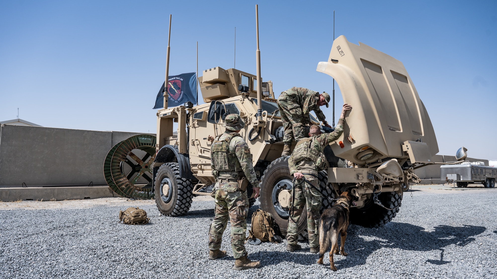 U.S. Air Force Airmen and military working dog Lucky, from the 386th Expeditionary Security Forces Squadron, take a look under the hood of a Mine Resistant Ambush Protected All-Terrain Vehicle (M-ATV) during vehicle familiarity training for the MWD handlers at Ali Al Salem Air Base, Kuwait, July 13, 2023. The M-ATV is designed to provide the same levels of protection as the larger and heavier vehicles, but with enhanced mobility in the region’s rough terrain. (U.S. Air Force photo by Staff Sgt. Kevin Long)