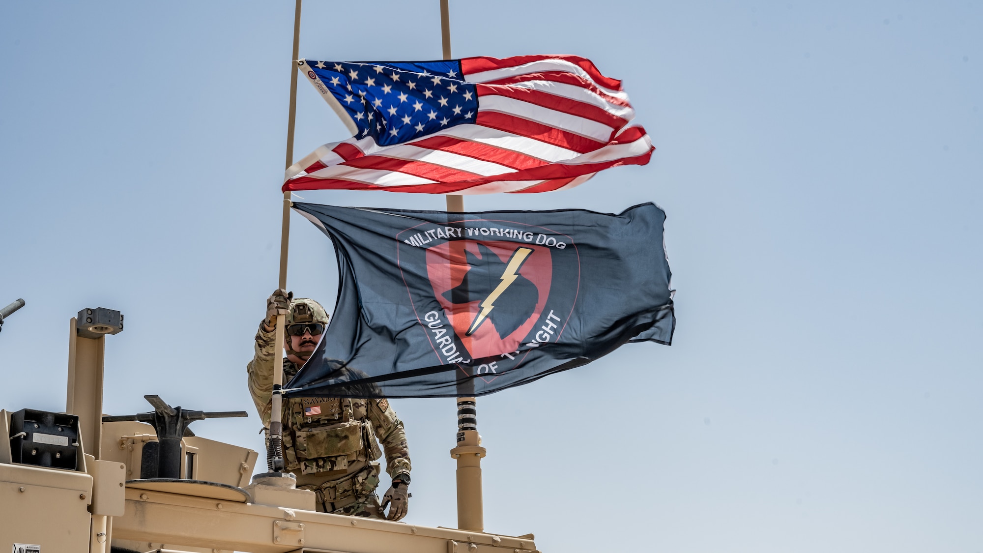 U.S. Air Force Tech. Sgt. Daniel Sayarot, 386th Expeditionary Security Forces Squadron military working dog handler, raises the U.S. and MWD flags on a Mine Resistant Ambush Protected All-Terrain Vehicle (M-ATV) during vehicle familiarity training at Ali Al Salem Air Base, Kuwait, July 13, 2023. The M-ATV is designed to provide the same levels of protection as the larger and heavier vehicles, but with enhanced mobility in the region’s rough terrain. (U.S. Air Force photo by Staff Sgt. Kevin Long)