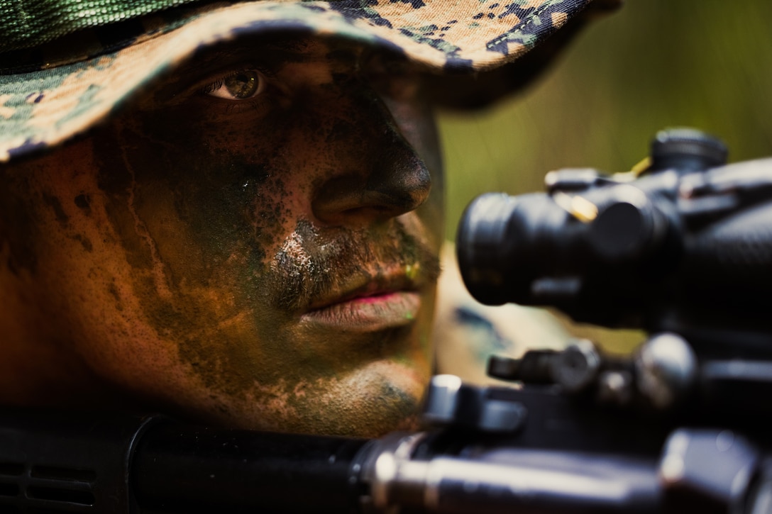 A Marine looks at the gun sight of his weapon.