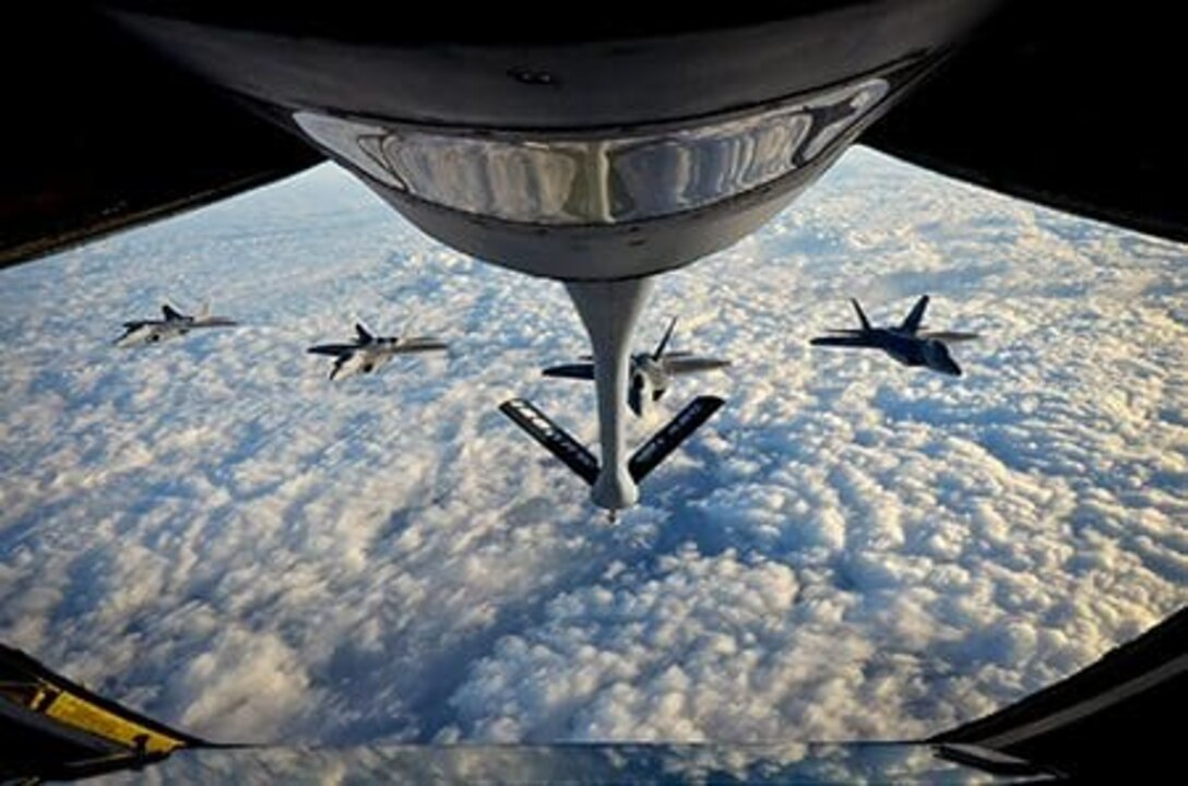 F-22 Raptors from Langley Air Force Base fly in formation behind a KC-135 Stratotanker from the Wisconsin Air National Guard's 128th Air Refueling Wing for mid-flight refueling Nov. 14, 2014. The F-22 Raptors were in route to Green Bay, Wis., to fly over Lambeau Field prior to a Green Bay Packers game. Air National Guard. Photo by Col. Jeff Cashman.