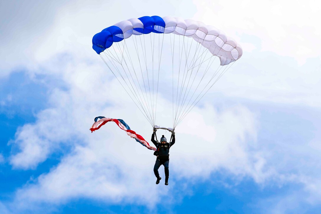 An airman descends in the sky wearing a parachute.