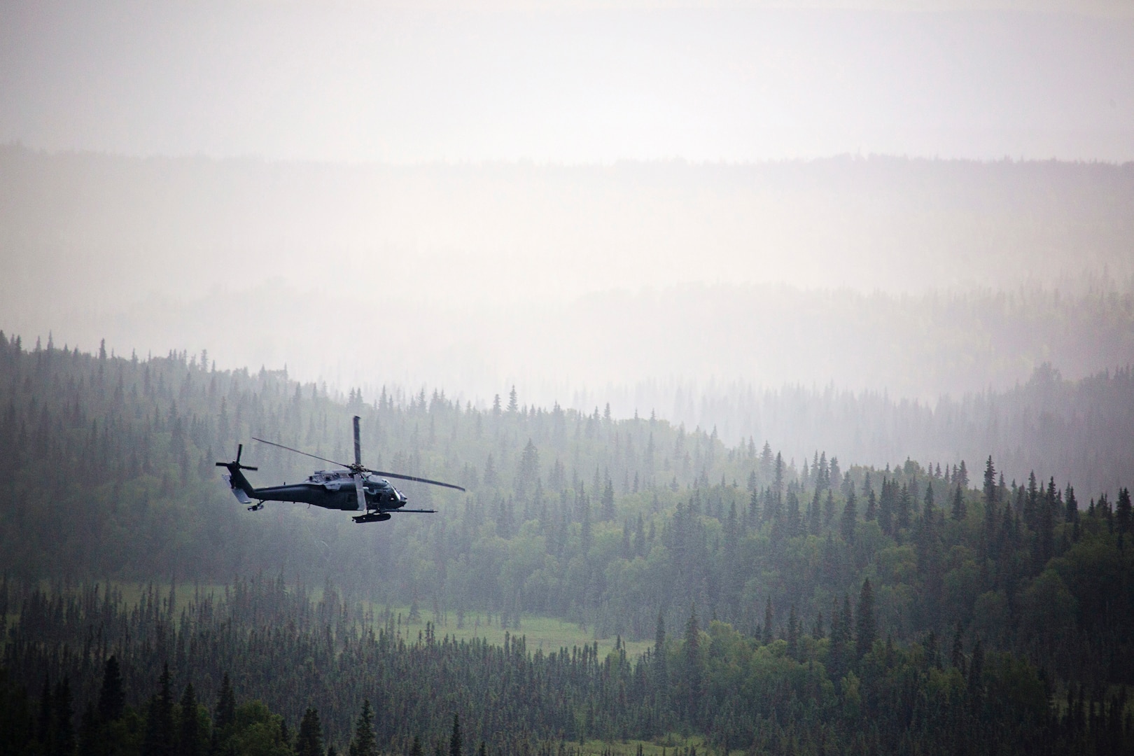 An Alaska Air National Guard HH-60 Pave Hawk helicopter from the 210th Rescue Squadron performs a simulated search and rescue pattern near the Little Susitna River in Alaska. The Pave Hawk conducts day and night personnel recovery operations during war, civil search and rescue, medical evacuation and disaster response operations.
