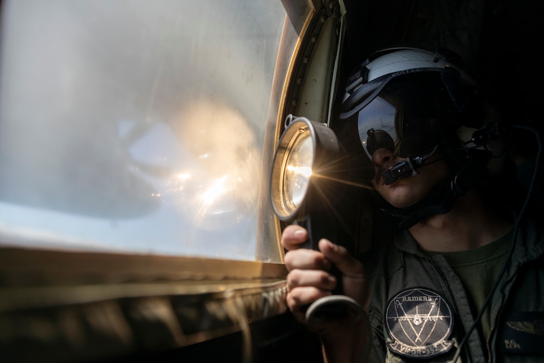 U.S. Marine Corps Lance Cpl. River Danvers, a loadmaster with Marine Aerial Refueler Transport Squadron 352, Marine Aircraft Group 11, 3rd Marine Aircraft Wing, signals to aircraft with an Aldis lamp during Exercise Talisman Sabre 23 near Royal Australian Air Force Base Darwin, Northern Territory, Australia, July 21, 2023. Talisman Sabre is the largest bilateral military exercise between Australia and the United States, with multinational participation, advancing a free and open Indo-Pacific by strengthening relationships and interoperability among key Allies and enhancing our collective capabilities to respond to various potential security concerns.