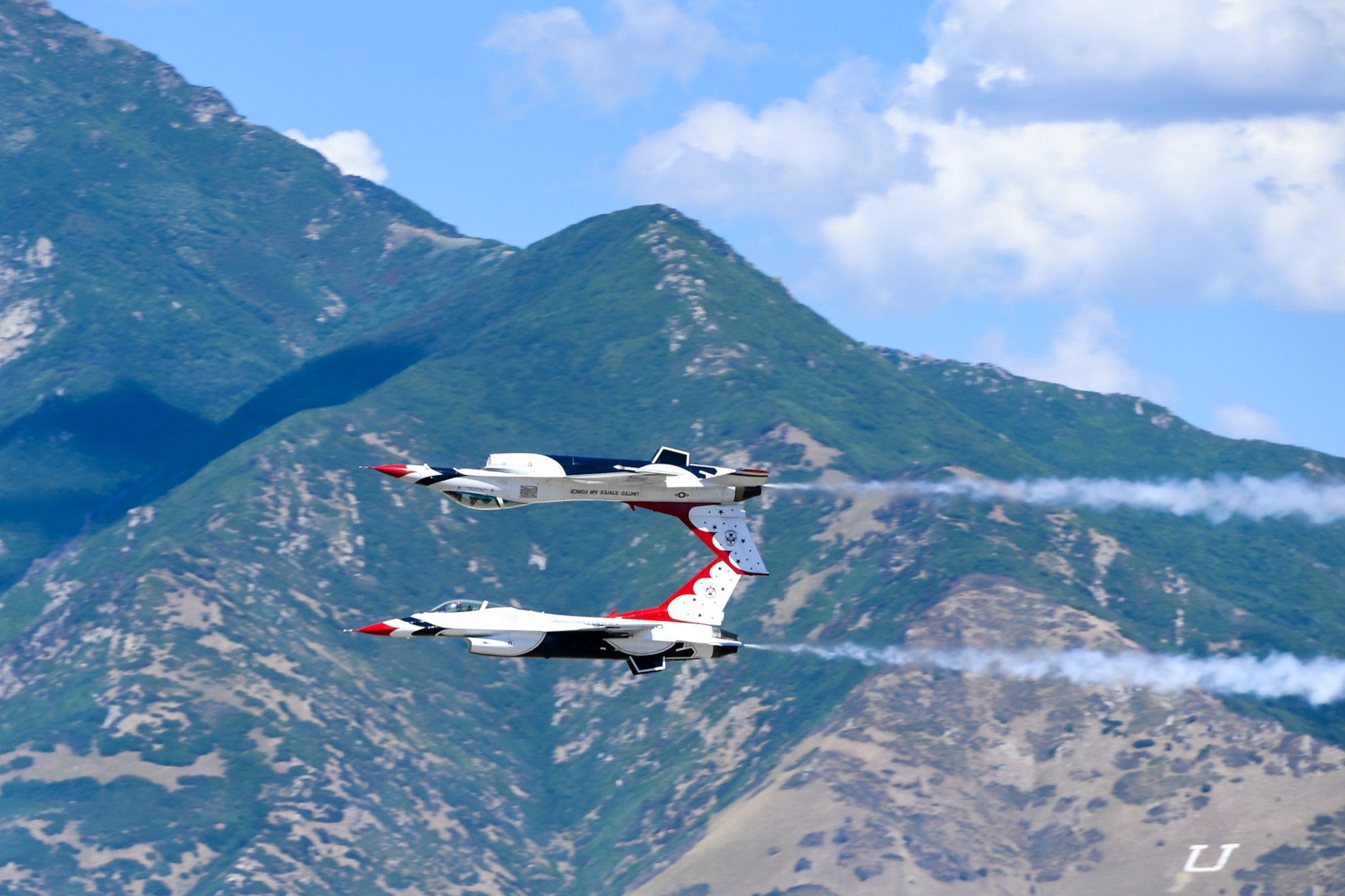 Two F-16 Thunderbirds flying with the wasatch mountains in the background