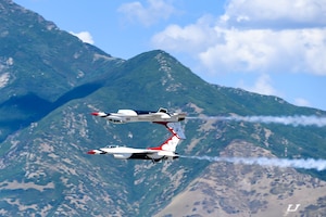 Two F-16 Thunderbirds flying with the wasatch mountains in the background