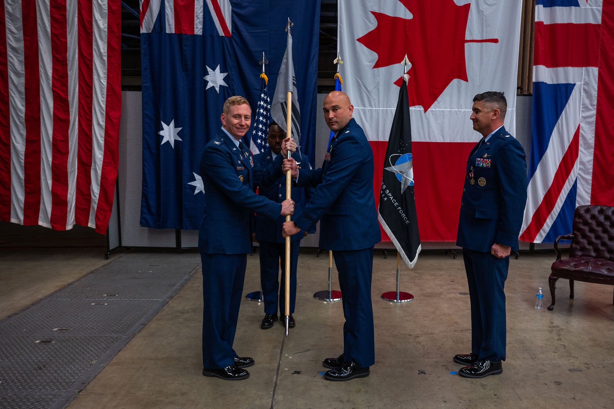 U.S. Space Force Col. Christopher Kenedy, Space Delta 6 commander, right, presents the 65th Cyberspace Squadron (65 CYS) guidon to Lt. Col. Jacob Majewski, incoming 65 CYS commander, middle, while Lt. Col. Jason Thompson, outoing 65 CYS commander, stands by during the 65 CYS change of command ceremony at Vandenberg Space Force Base, Calif., July 21, 2023. (U.S. Space Force photo by Tech. Sgt. Luke Kitterman)