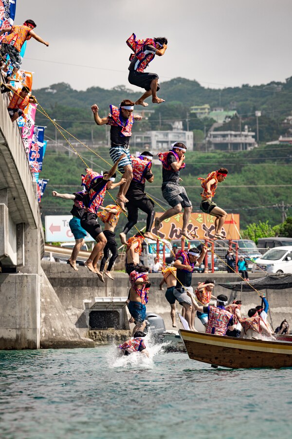 Competitors from the local East and West Ojima team jump from a bridge as part of an island tradition before the Ojima Island Dragon Boat Race in Nanjo City, Okinawa, Japan, June 21, 2023. Dragon boat racing was first introduced to Okinawa from China around 600 years ago and was popularized in southern cities. Dragon boat races are held every year on the fifth month of the Lunar calendar. Ojima Island’s dragon boat race has three teams per heat, and 11 members per team. (U.S. Marine Corps photo by Cpl. Thomas Sheng)
