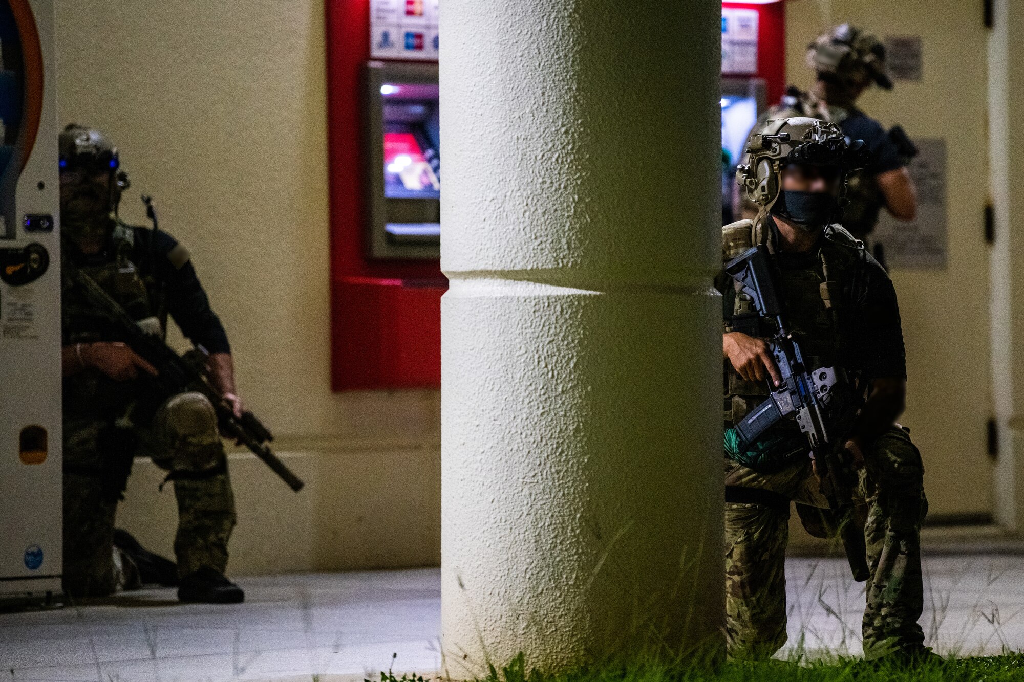 Three U.S. Army Green Berets take cover outside and secure an area.
