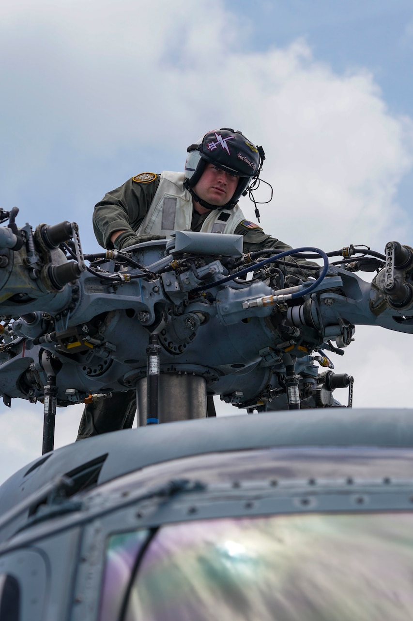 A sailor works on a helicopter.