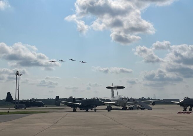 photo of four A-10Cs flying over an airborne warning and control system aircraft and two A-10Cs on the flight line.