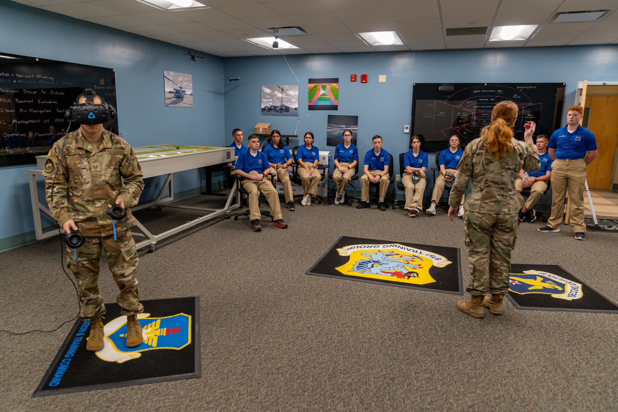 U.S. Air Force Tech. Sgt. Evan Carrasco, 334th Training Squadron, airfield management instructor, gives a VR demonstration on airfield management while Staff Sgt. Britney Diamond, 334th TRS air traffic control instructor, gives a brief to Pace High School Navy Junior ROTC cadets at Keesler Air Force Base, Mississippi, July 11, 2023.