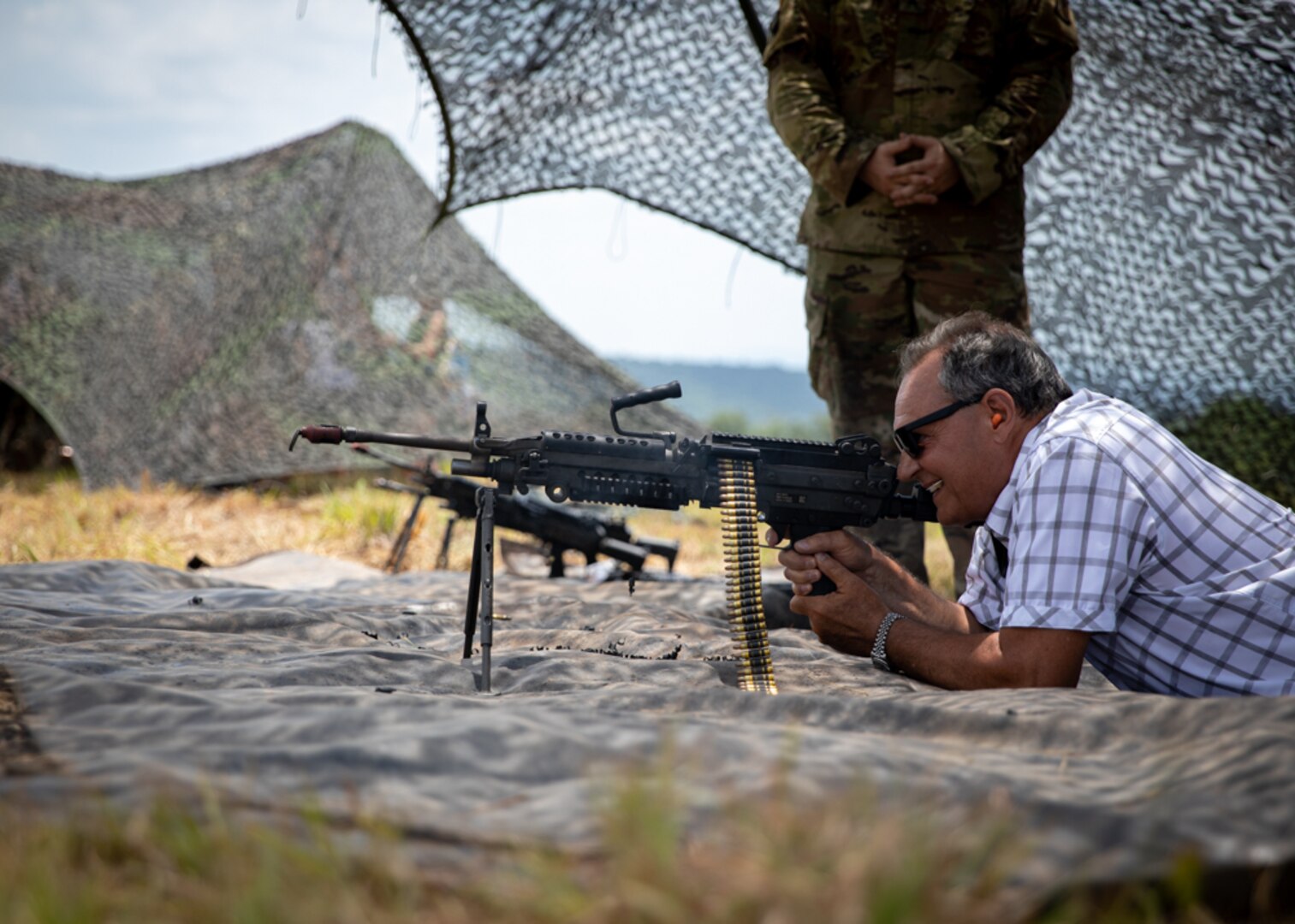 Photo of: Civilian employers of Soldiers of the 45th Field Artillery Brigade firing a machine gun.