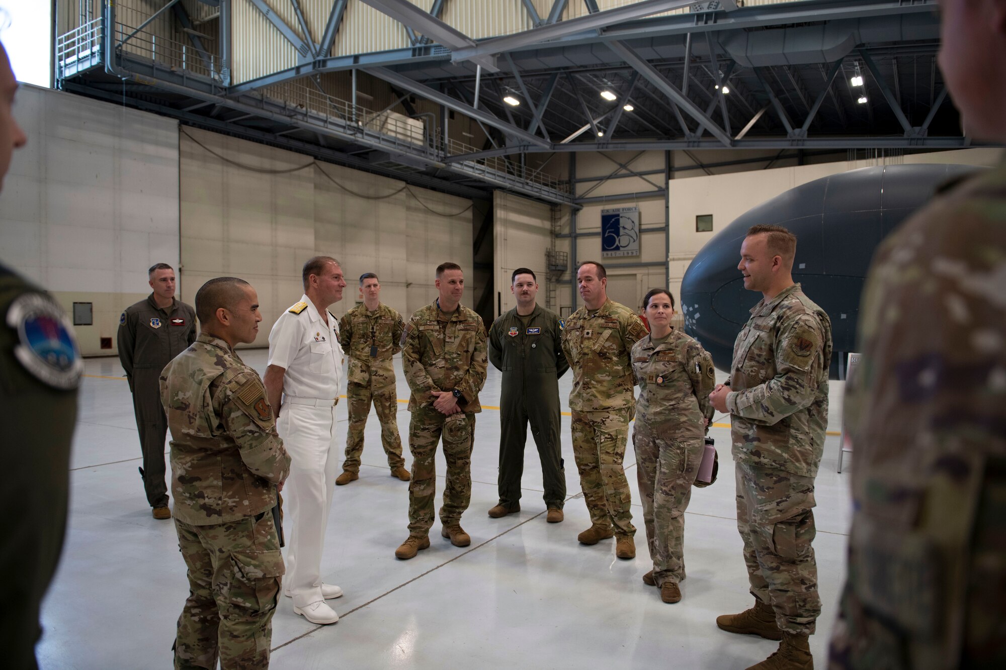 Service members stand and listen to each other speak.