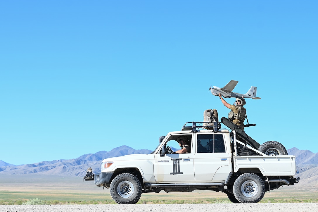 A sailor launches an unmanned aircraft system from the back of a military vehicle.