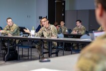 People, some in army uniform, are talking while seated and at long tables