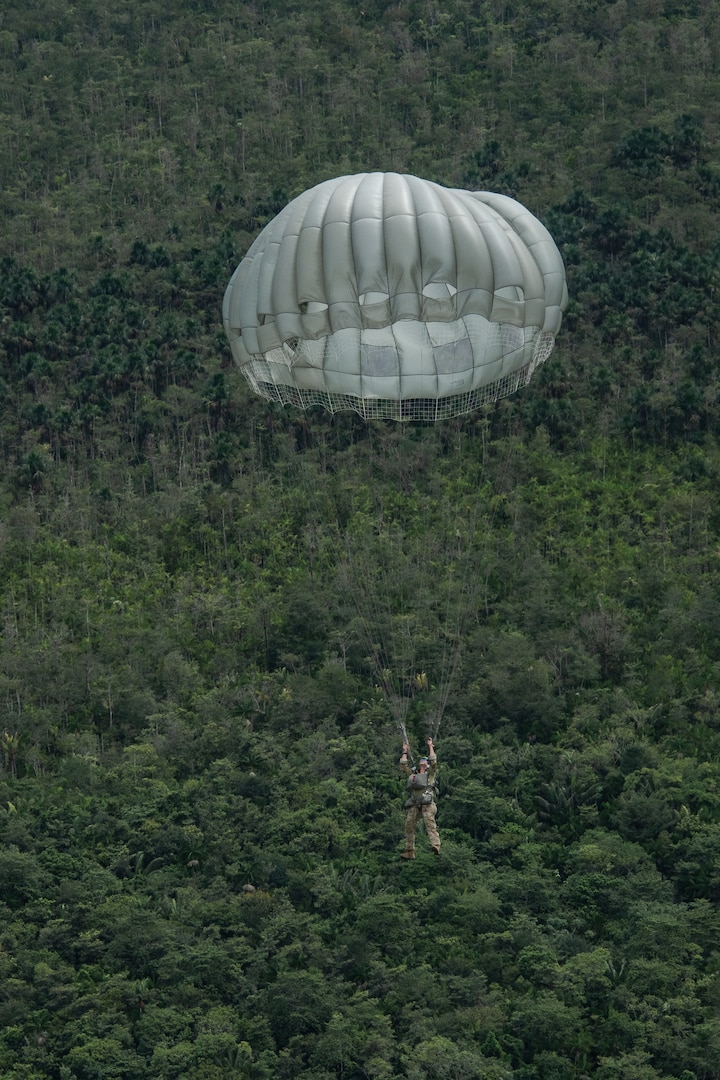 Photo: A servicemember parachutes into Air Base London, Guyana, during TRADEWINDS23 Exercise July 18, 2023. The different training components of the exercise are focused on increasing regional cooperation throughout the Caribbean and Caribbean Basin. (U.S. Air National Guard photo by Tech. Sgt. Brigette Waltermire)