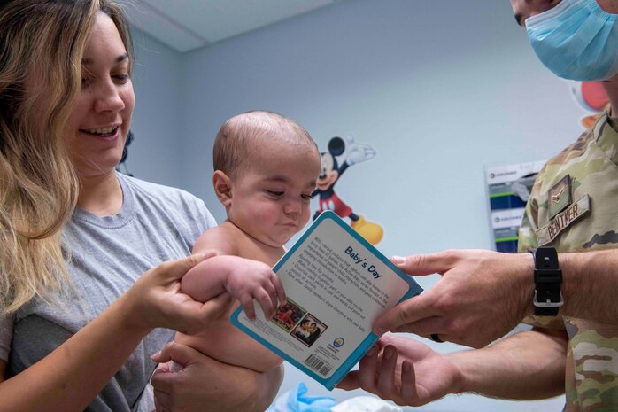 U.S. Air Force Airman Nicholas Beintker, 9th Healthcare Operations Squadron aerospace medical service technician, gives a book to a Alexis Blumer and her son Atticus Blumer during a clinical visit at the pediatrics clinic June 19, 2023, at Beale Air Force Base, California.