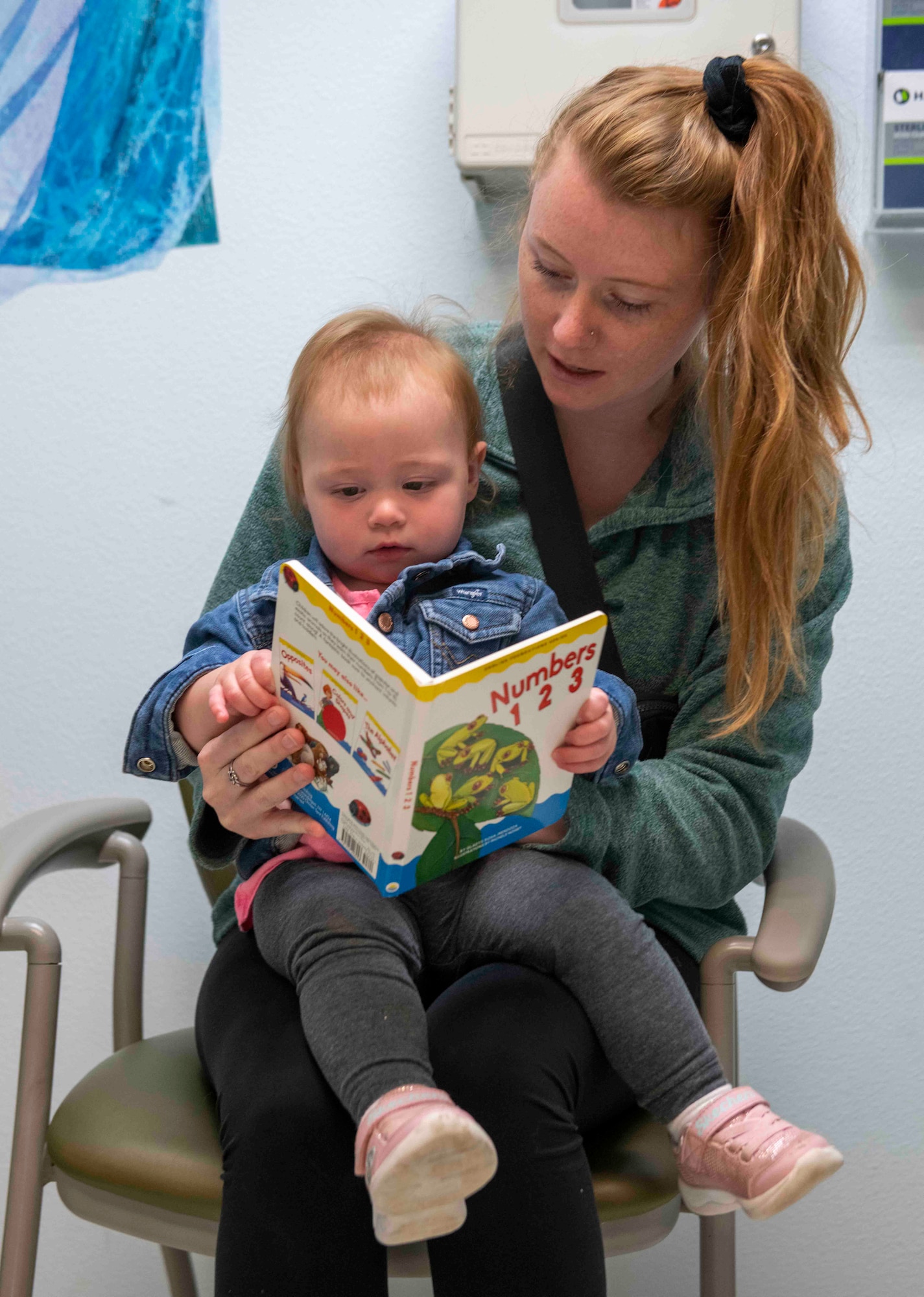 Nicole Hales reads to her daughter Emerson Hales after receiving a book for the Reach Out and Read Initiative during a clinical visit at the pediatrics clinic June 19, 2023, at Beale Air Force Base, California.