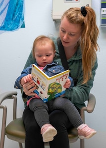 Nicole Hales reads to her daughter Emerson Hales after receiving a book for the Reach Out and Read Initiative during a clinical visit at the pediatrics clinic June 19, 2023, at Beale Air Force Base, California.
