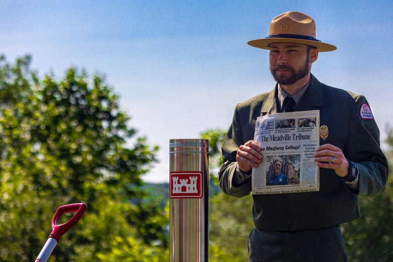 Ryan Hill, the supervisory natural resource specialist at Woodcock Creek Lake, places a daily edition of the Meadville Tribune in a time capsule in Saegertown, Pennsylvania, July 14, 2023. Community leaders and Corps of Engineers employees gathered on a summer morning to celebrate Woodcock Creek Dam’s 50th anniversary. The corps built Woodcock Creek Dam to reduce floods along the French Creek, saving communities such as Saegertown and Meadville from catastrophic flooding year after year and has prevented more than $38 million in flood damages since its construction in 1973. The time capsule will be opened during the dam’s 100th celebration in 2073. (U.S. Army Corps of Engineers Pittsburgh District photo by Andrew Byrne)