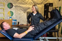 A strength coach, tries out compression pants designed to assist with muscle recovery as part of a demonstration by a certified athletic trainer.