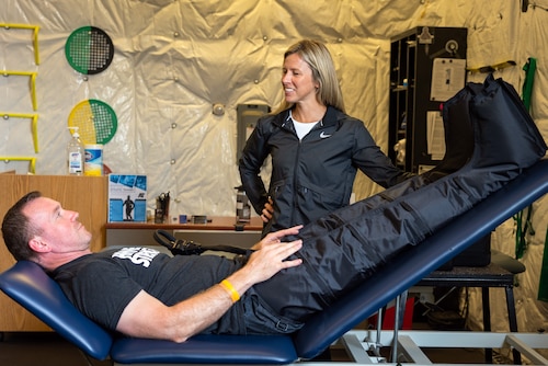 A strength coach, tries out compression pants designed to assist with muscle recovery as part of a demonstration by a certified athletic trainer.