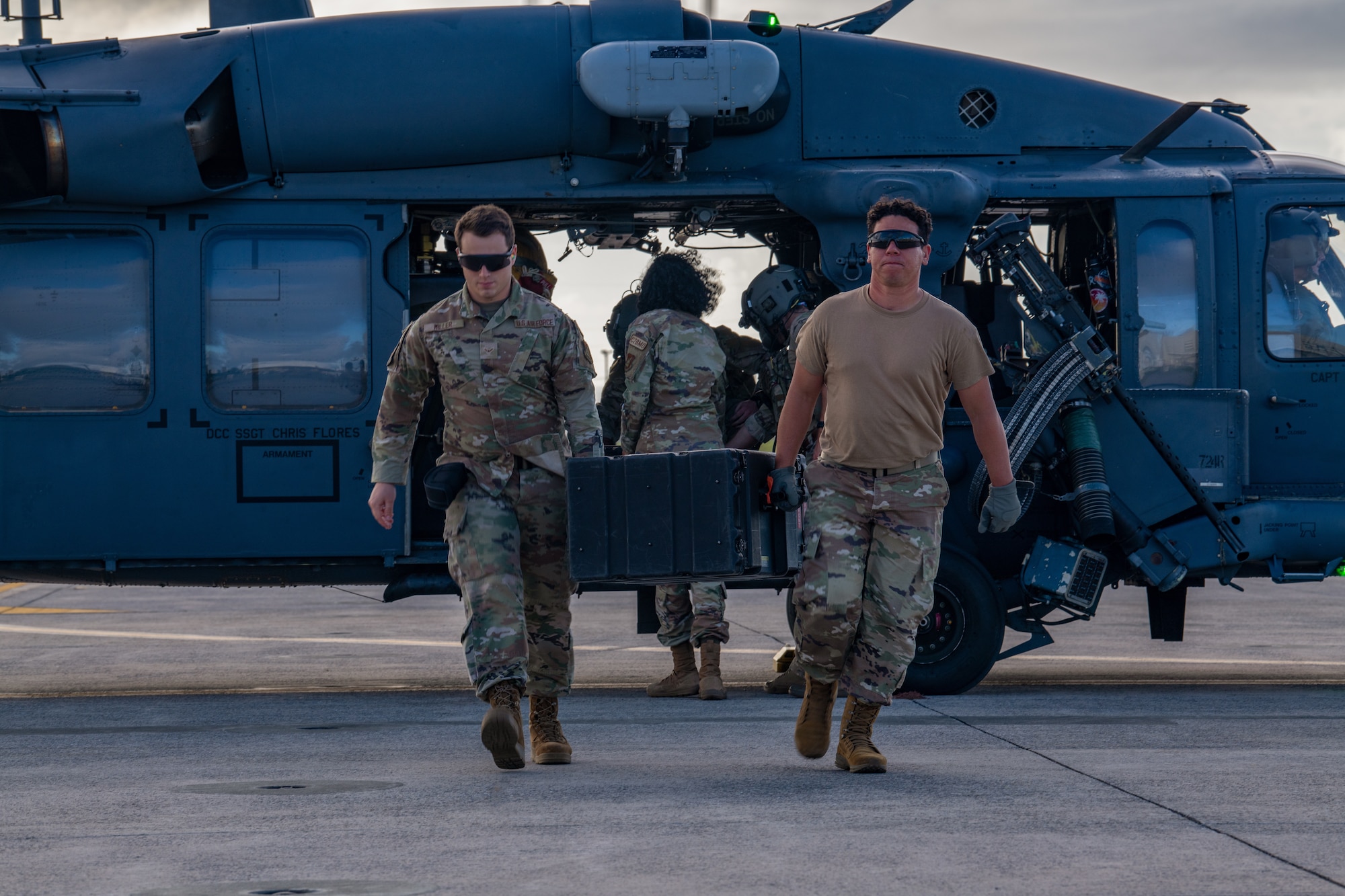 Airmen carry a case away from a helicopter.