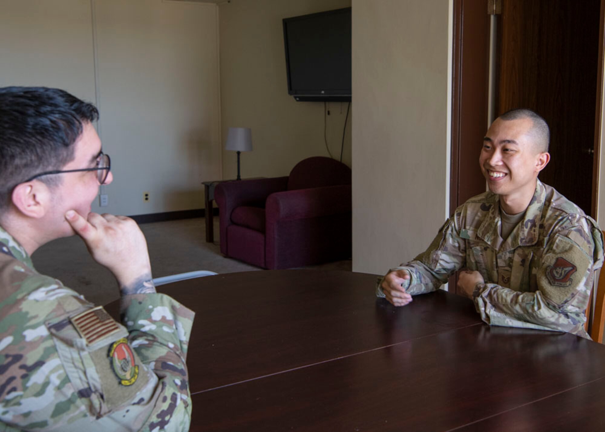 Two military men sit across from each other at a dining table.