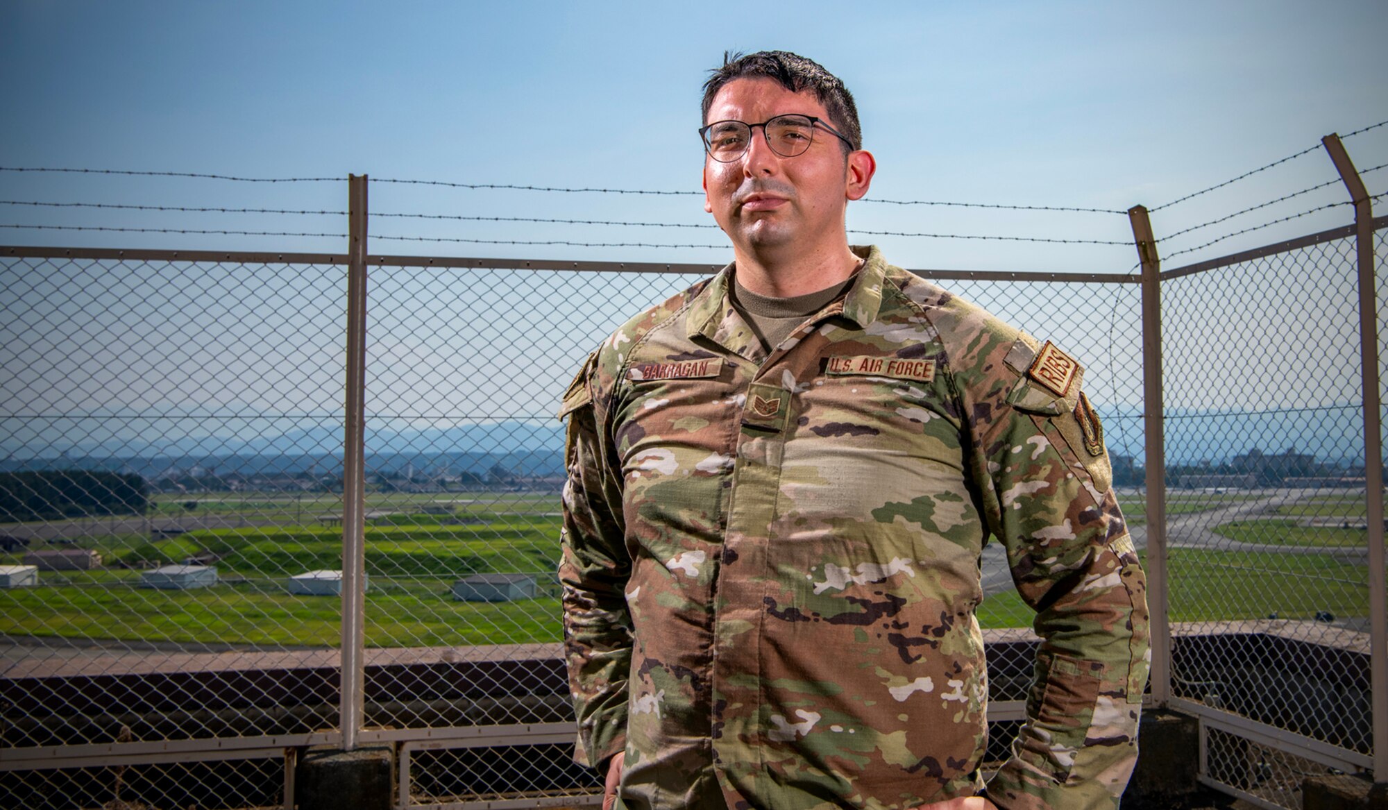 Military man stands with hands on hips.